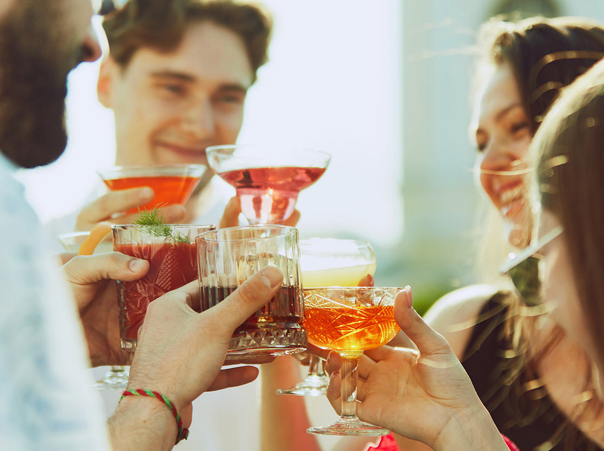 group of friends with various cocktails performing a toast 